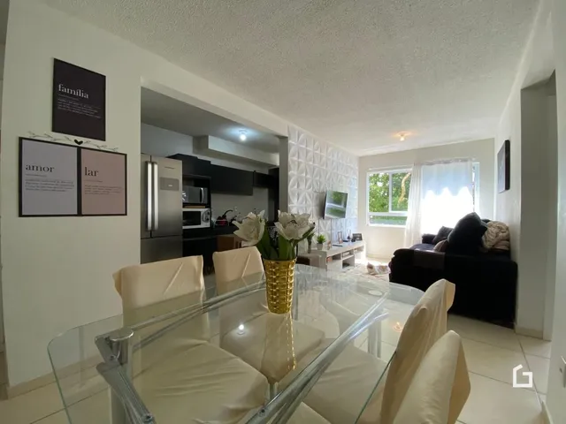 Sala de estar com mesa de jantar de vidro e sofá em um apartamento.