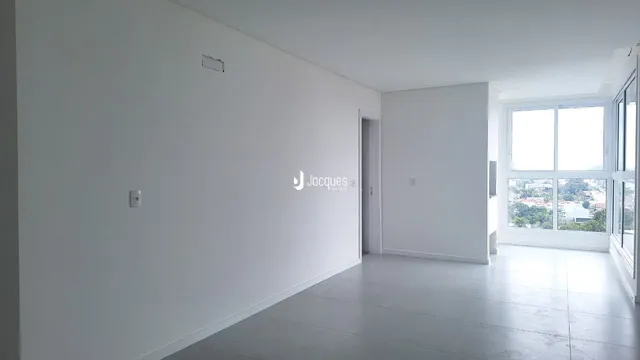 Interior de uma sala com paredes brancas e piso claro.