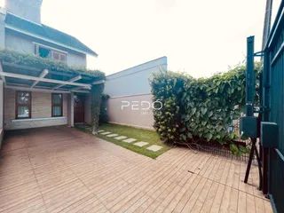 Vista externa de uma residência com deck de madeira e vegetação densa.