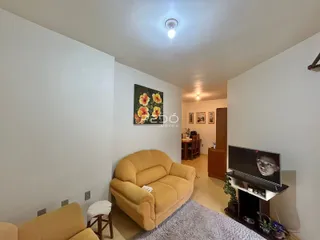 Sala de estar com sofá amarelo e decoração de parede em um apartamento.