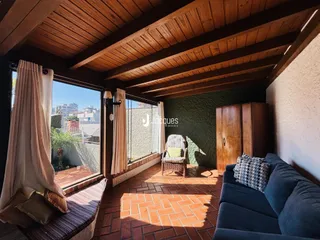 Sala de estar com piso de tijolo e teto de madeira em um imóvel no Brasil.