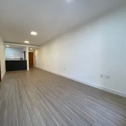 Corredor interno com piso de madeira clara.