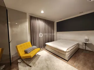 Quarto com cama e poltrona amarela em um apartamento.