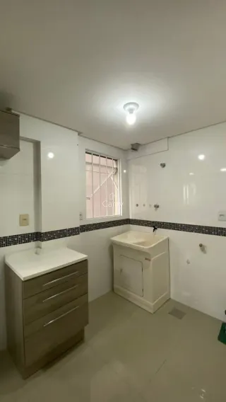 Vista de um ambiente interno com bancada e armários brancos.