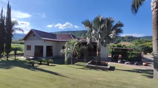 Fachada de uma casa em Lajeado, Brasil, com jardim verde e palmeiras sob um céu azul.