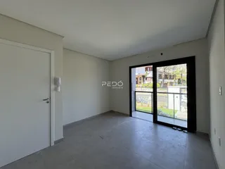Ambiente interno de uma sala com piso de concreto e porta de vidro.