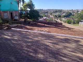 Vista externa de uma residência com muro de tijolos e área pavimentada.
