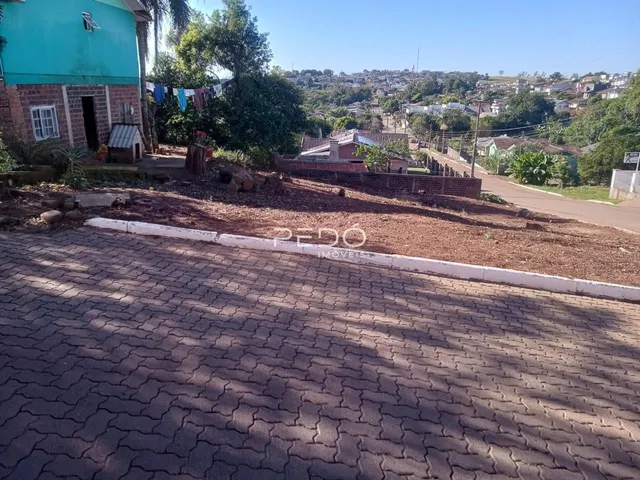 Vista externa de uma residência com muro de tijolos e área pavimentada.
