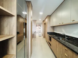 Vista de um corredor moderno com armários de madeira e bancadas escuras.