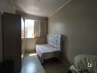 Quarto com cama e porta de acesso a outra área.
