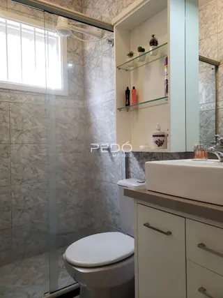 Foto de um banheiro com revestimento de azulejo branco e box de vidro.