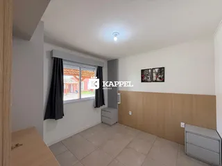 Uma sala de estar clara com janelas e painéis de madeira na parede.