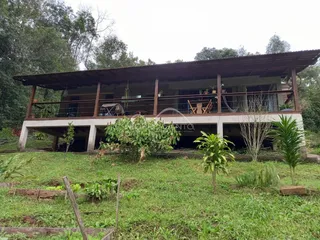 Fachada de uma casa elevada com varanda e jardim gramado.