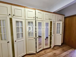 Corredor interno com portas brancas e piso de madeira.