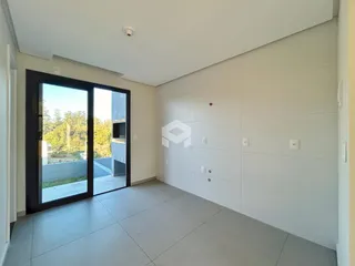 Interior de uma sala ampla com porta de vidro abrindo para o exterior.