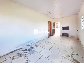 Foto de um ambiente interno com paredes brancas e piso de cerâmica desgastado.