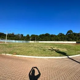 Vista externa de um terreno com gramado e área pavimentada.