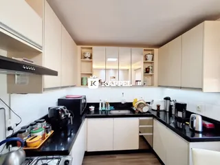Cozinha moderna com armários brancos e bancadas escuras em um imóvel em Lajeado.