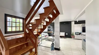 Vista de um corredor com escadaria de madeira em uma residência.