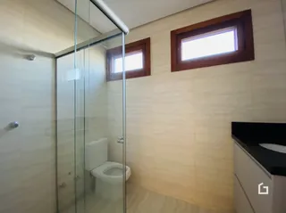 Banheiro com divisória de vidro e piso de madeira.