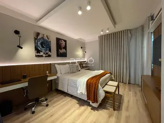 Quarto moderno com cabeceira de madeira e piso de madeira clara.