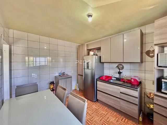 Interior de uma cozinha com armários brancos e piso de cerâmica em Lajeado.