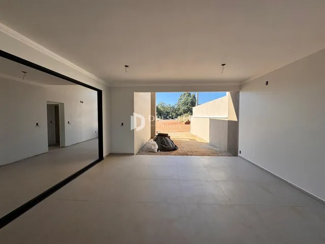 Ambiente interno de uma sala ampla com paredes brancas e piso claro.
