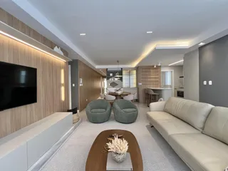 Sala de estar moderna com sofá e poltronas em um ambiente claro.
