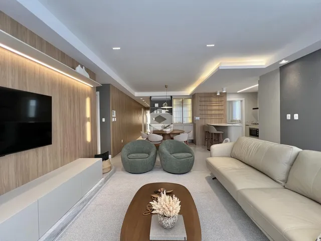 Sala de estar moderna com sofá e poltronas em um ambiente claro.