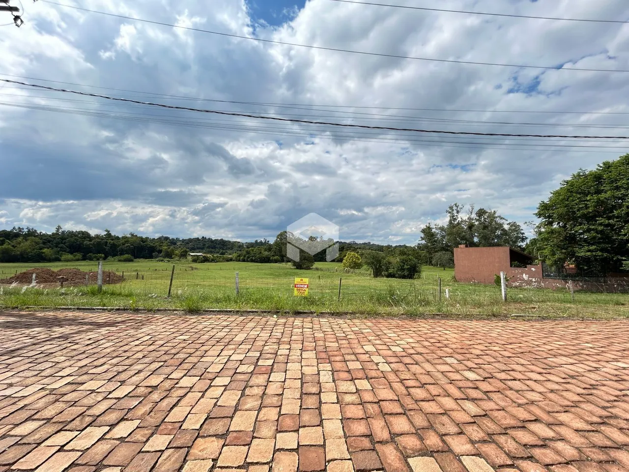 Vista externa de uma propriedade com campo gramado e cerca de arame.