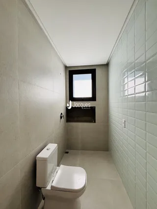 Foto de um banheiro com paredes revestidas de azulejos claros.