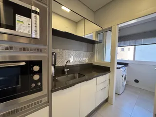 Cozinha moderna com armários brancos e bancada escura.