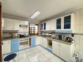 Foto de uma cozinha com armários brancos e piso de cerâmica.