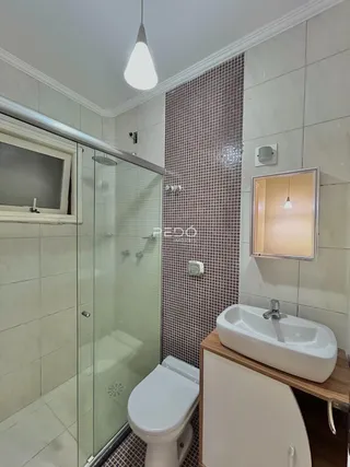 Interior de um banheiro com box de vidro e revestimento de azulejos.
