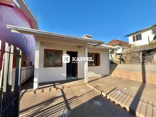 Vista externa da casa com um pátio coberto e piso de cerâmica.