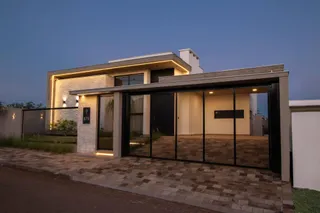Fachada moderna de uma residência em Lajeado, Brasil, com iluminação externa.