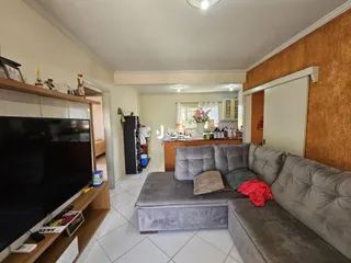 Sala de estar com sofá cinza e televisão em um imóvel no Brasil.