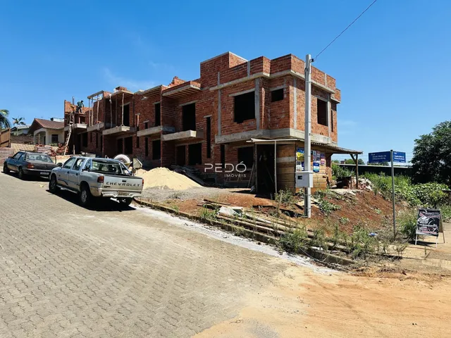 Fachada de um prédio em construção em Lajeado, Brasil, ao lado de uma estrada de terra.