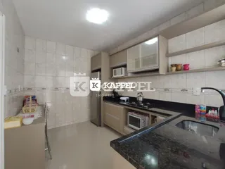 Cozinha com armários e bancadas escuras em um imóvel.