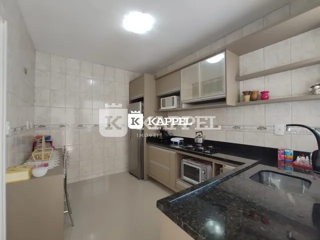 Cozinha com armários e bancadas escuras em um imóvel.