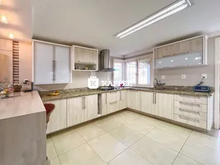 Cozinha moderna com armários brancos e bancadas claras.