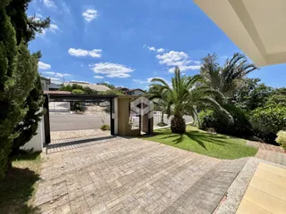 Vista externa do terreno com portão e jardim.