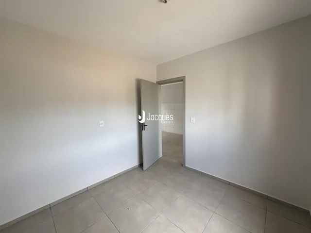 Corredor interno com paredes brancas e piso de cerâmica.