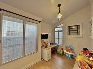 Ambiente interno de uma sala com piso de madeira e grandes janelas.