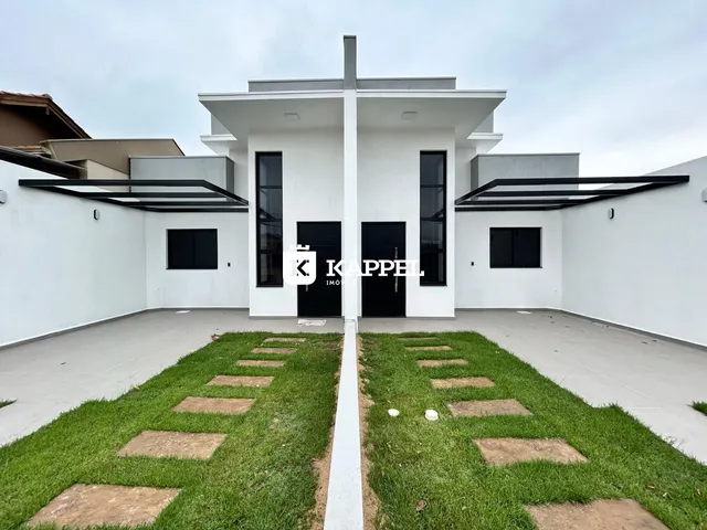 Fachada moderna de uma casa branca com paisagismo frontal.