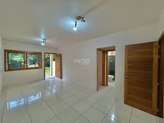 Sala de estar com piso de cerâmica branca e janelas de madeira.