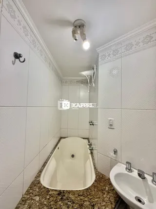 Banheiro com banheira e vaso sanitário revestido de azulejos brancos.