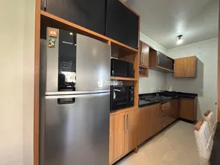 Vista interna de uma cozinha com armários de madeira e eletrodomésticos em aço inoxidável.