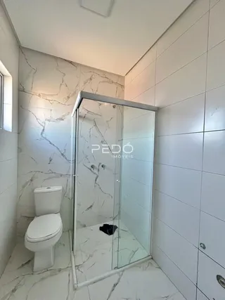 Foto de um banheiro com revestimento de mármore branco e box de vidro.
