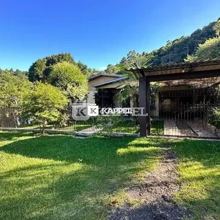 Vista externa de um jardim gramado com vegetação ao fundo.